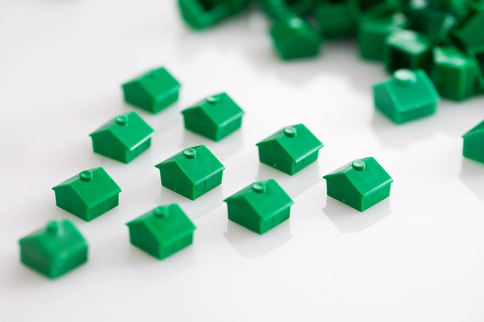 green toy hous figurines arranged in triangular pattern on the table